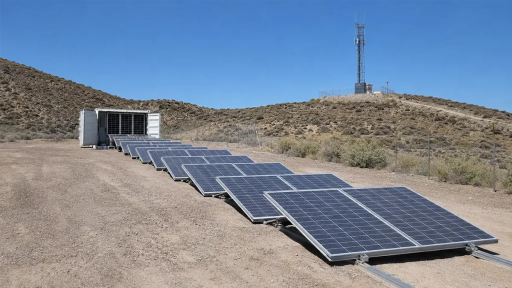 Fold-out solar container deployed at a remote telecom site with ground-mounted sliding solar panels extended from the container